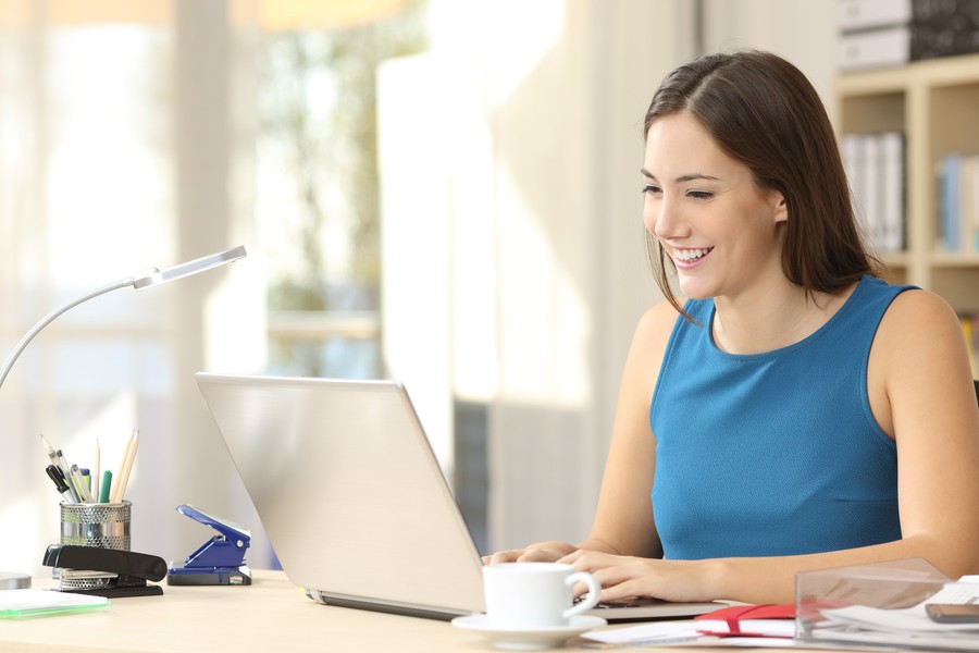 A woman typing on a laptop in a home office