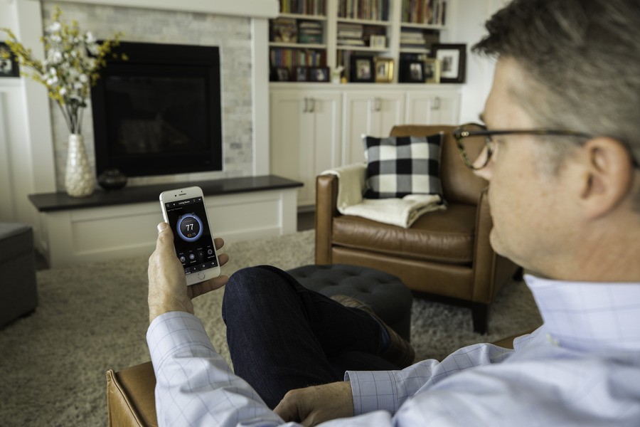 A man looking at the smart home control app on his cell phone.